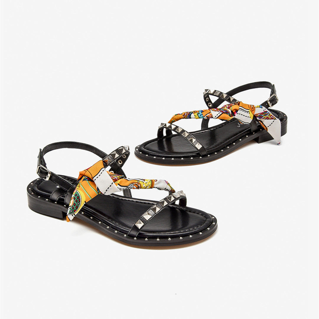 Black sandals with decorative straps on a white background