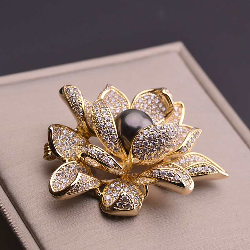 Gold brooch with central black gemstone on a beige surface