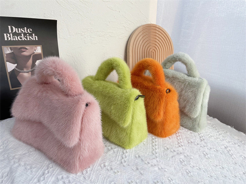 Four colorful fluffy handbags on a textured surface with a magazine in the background.