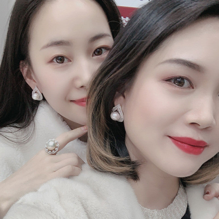 Two women wearing pearl earrings with a blurred background