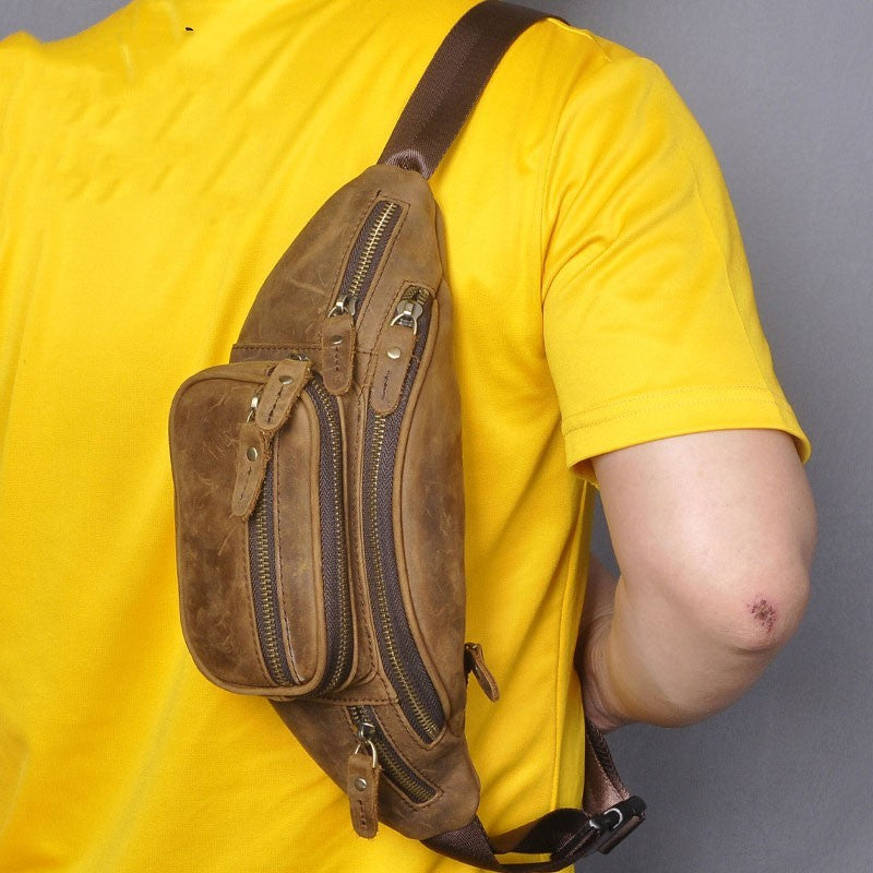 Person wearing a brown leather sling bag over a yellow shirt against a gray background