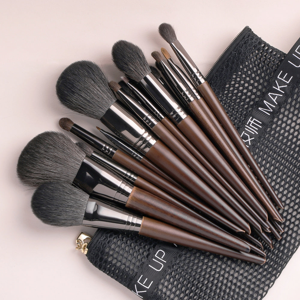 Set of makeup brushes with a black pouch on a light pink background