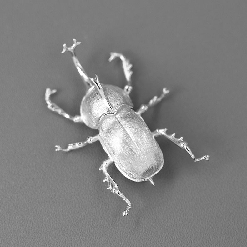 Silver beetle sculpture on a gray background