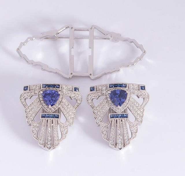 Pair of earrings with blue gemstones and diamond accents on a white background