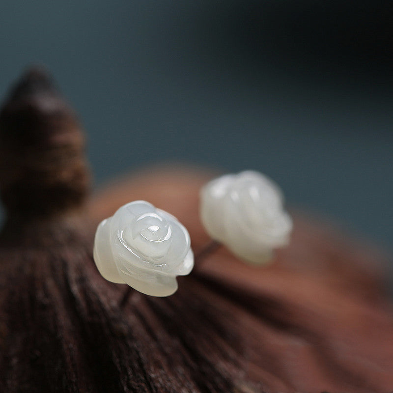 Two white rose-shaped objects on a wooden surface with a blurred background