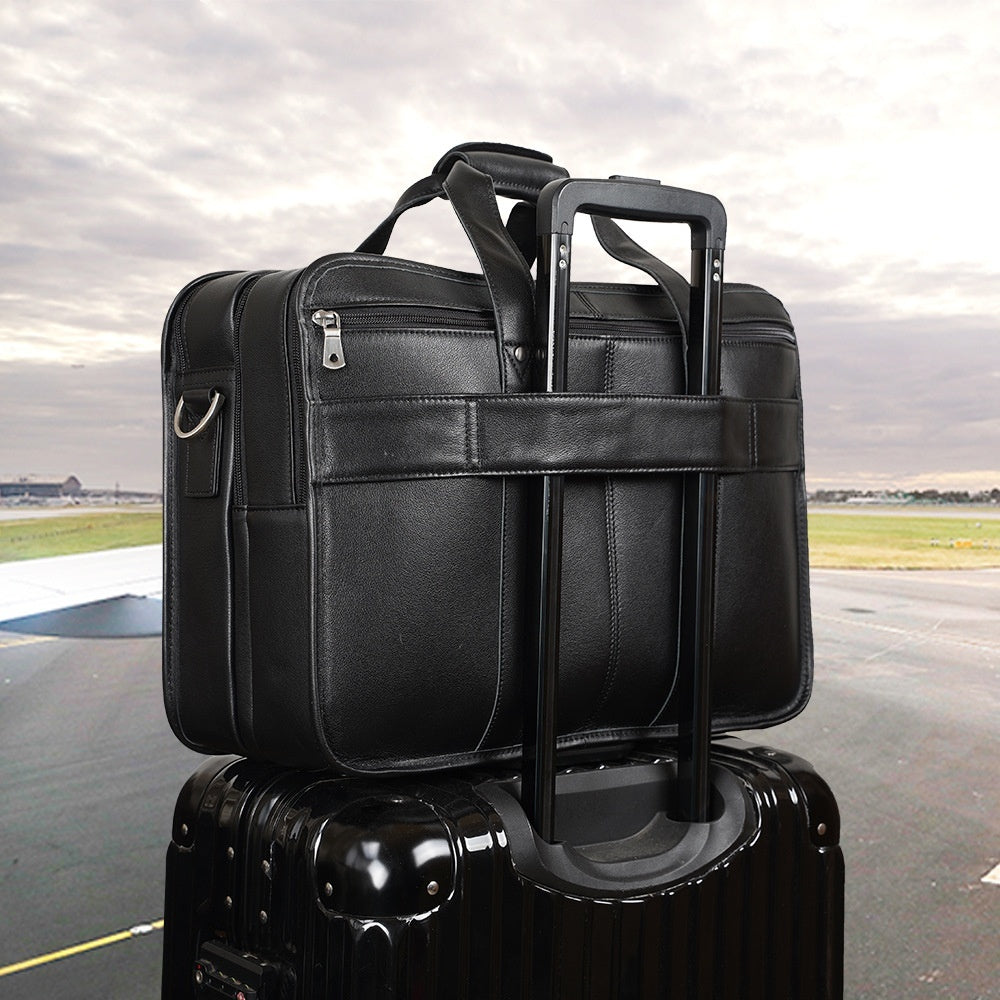 Black leather briefcase stacked on top of a suitcase with an airport tarmac in the background