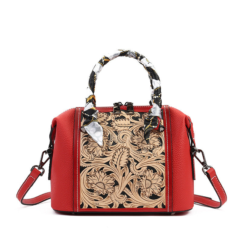 Red handbag with intricate black floral patterns on a white background