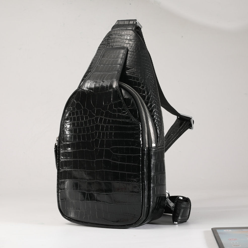 Black crocodile-patterned sling bag on a light gray background