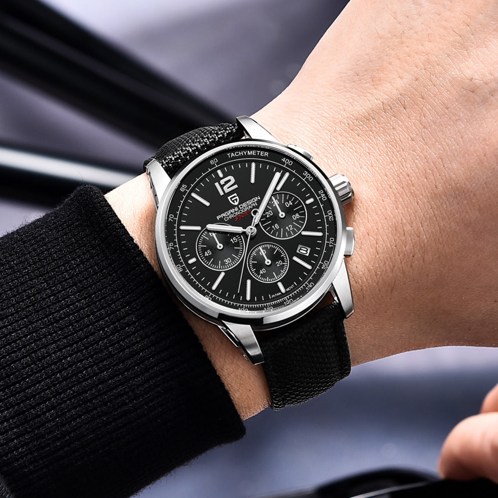 Black wristwatch with detailed face on a person's wrist, blurred background