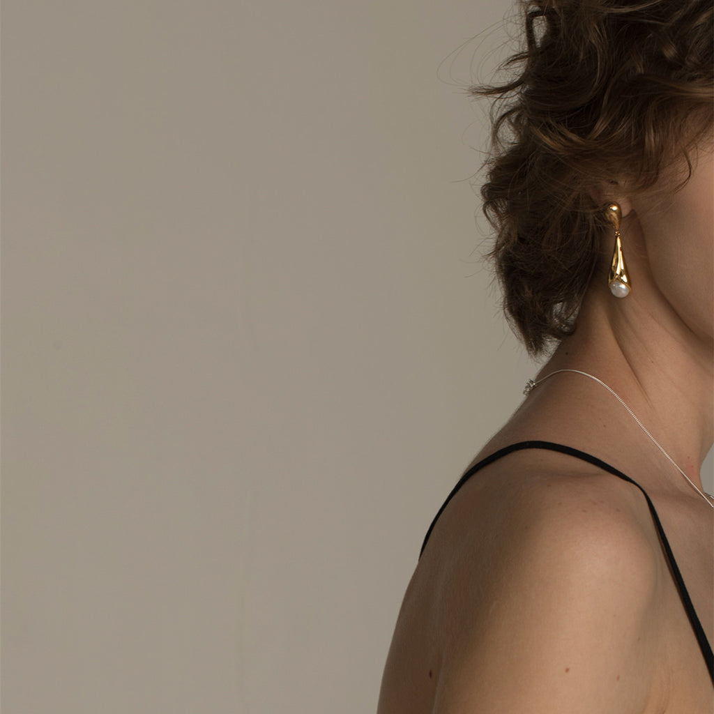 Woman wearing gold earrings with a neutral background
