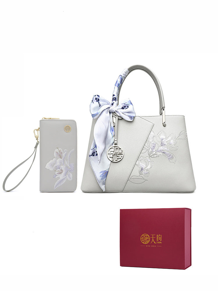 White handbag with floral embroidery, matching wallet, and red box on a white background