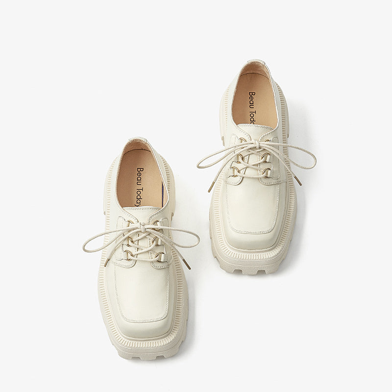 Pair of white sneakers with laces on a light gray background