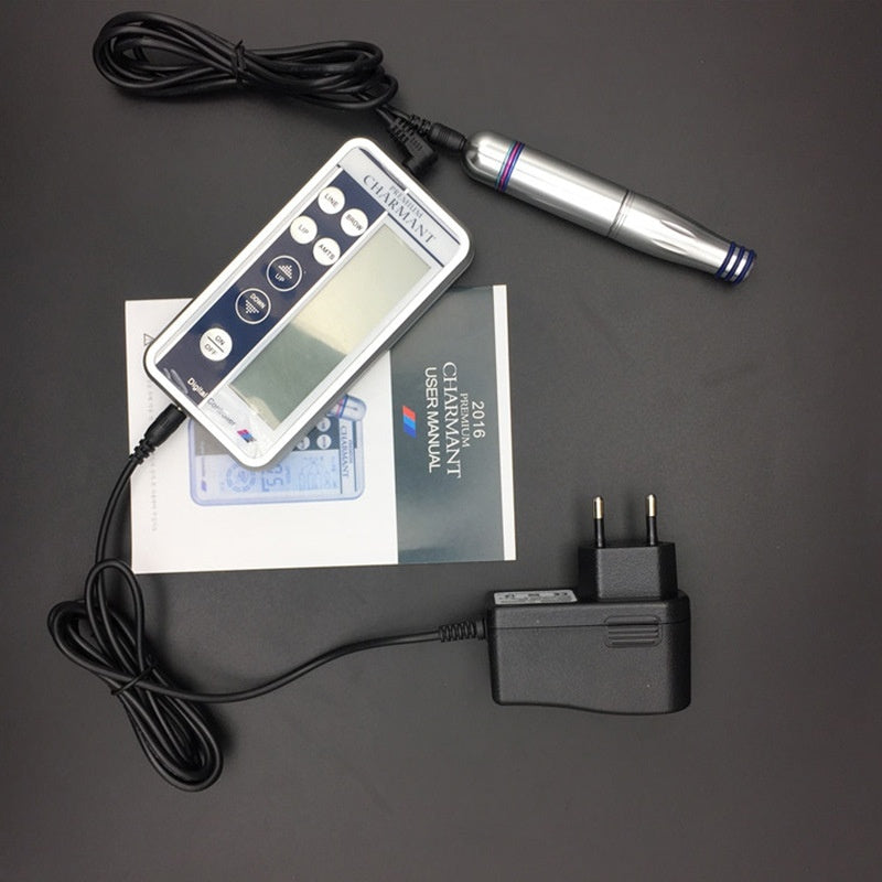 Tattoo machine, power adapter, and user manual on a dark surface