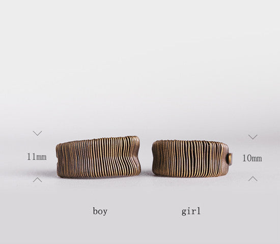 Two bronze bracelets labeled 'boy' and 'girl' on a light gray background