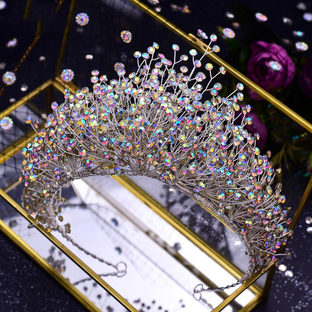 Sparkling tiara with multicolored crystals on a reflective surface