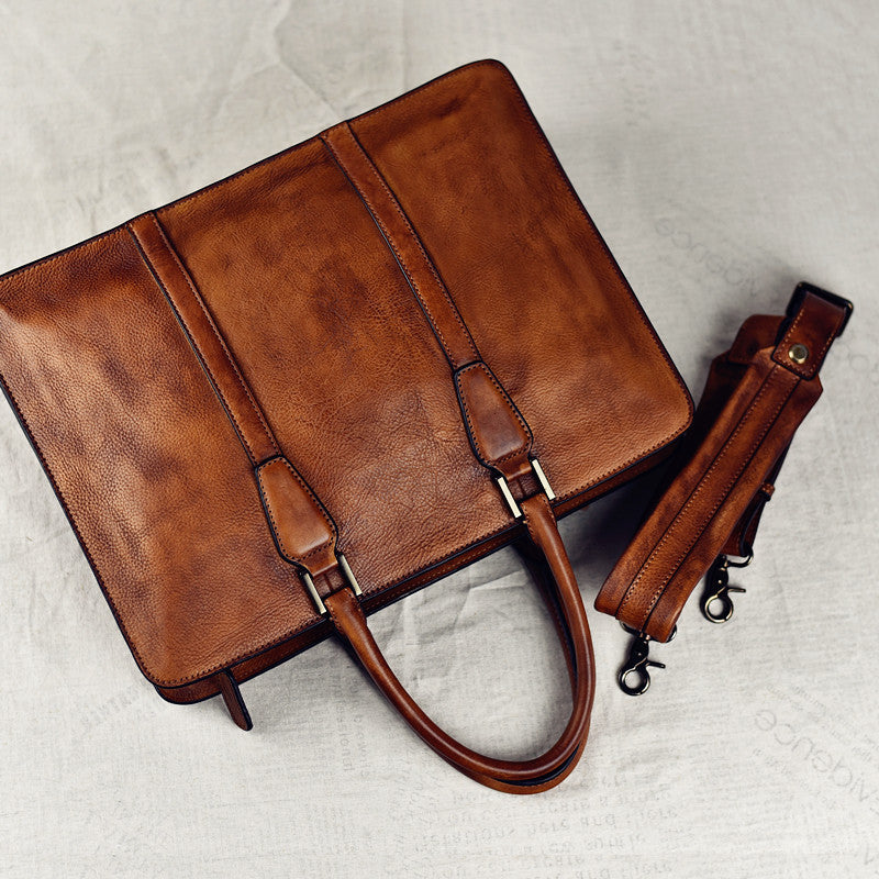 Brown leather briefcase with detachable strap on a light gray background