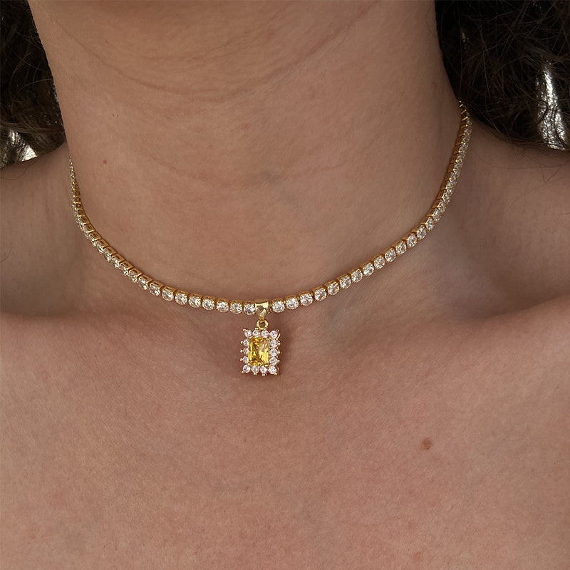 Necklace with a yellow gemstone pendant worn by a person