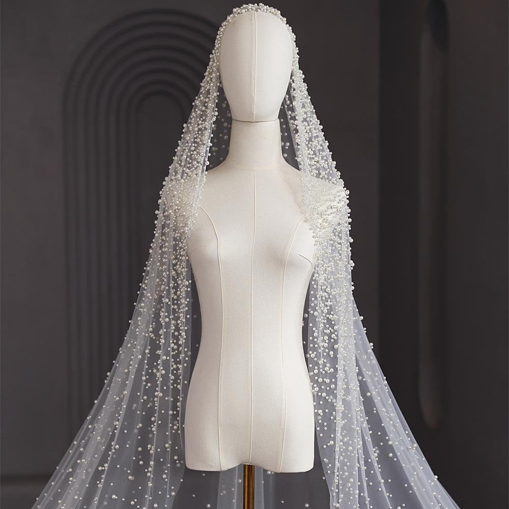 White beaded veil on a mannequin against a dark background