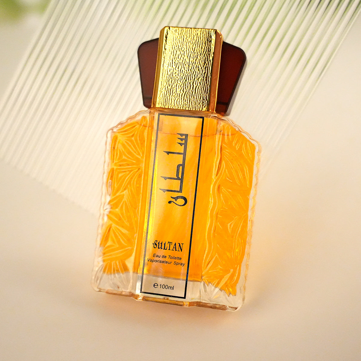 Perfume bottle with gold cap and orange packaging on a light background