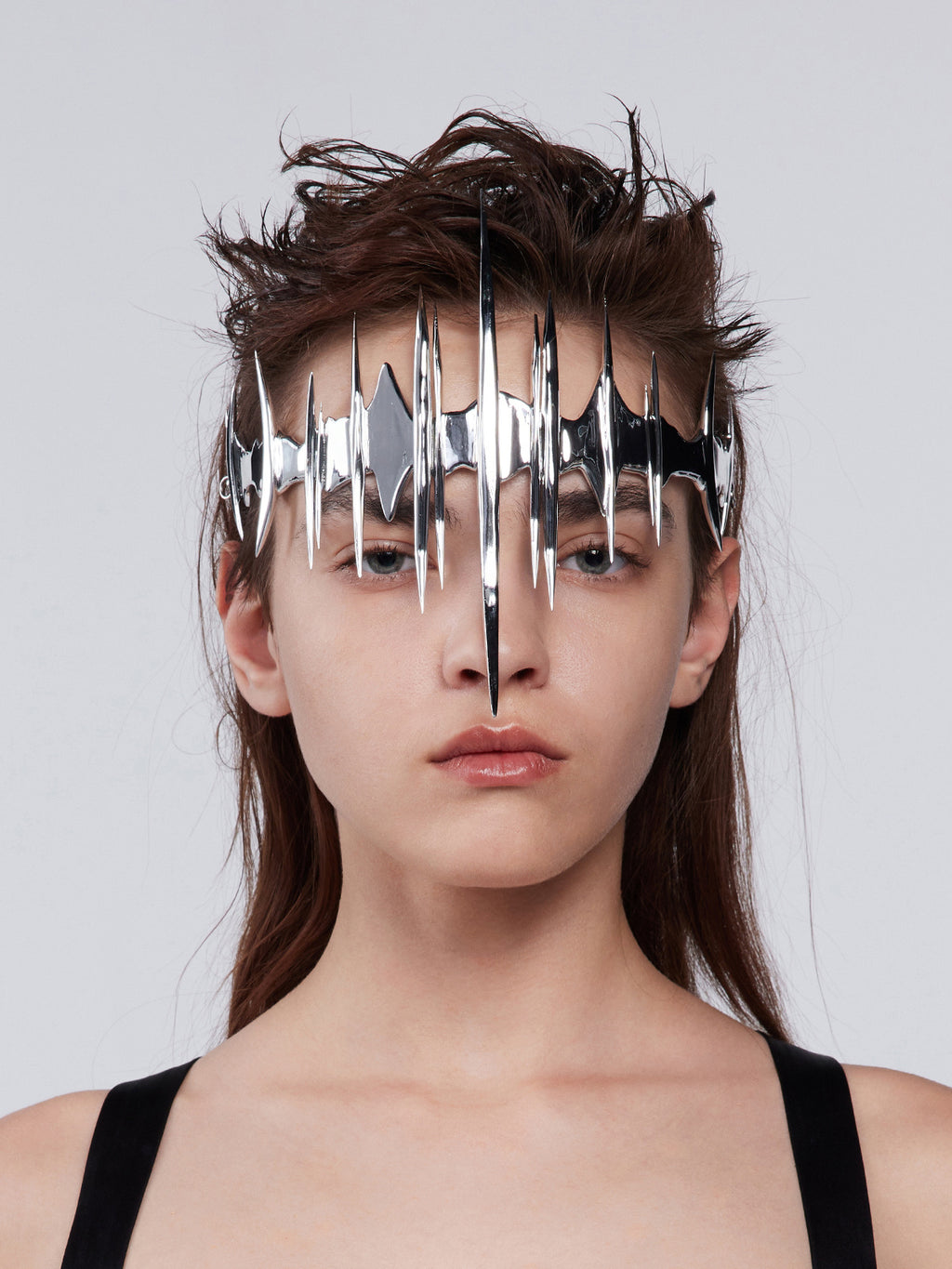 Person wearing a metallic face mask against a plain background