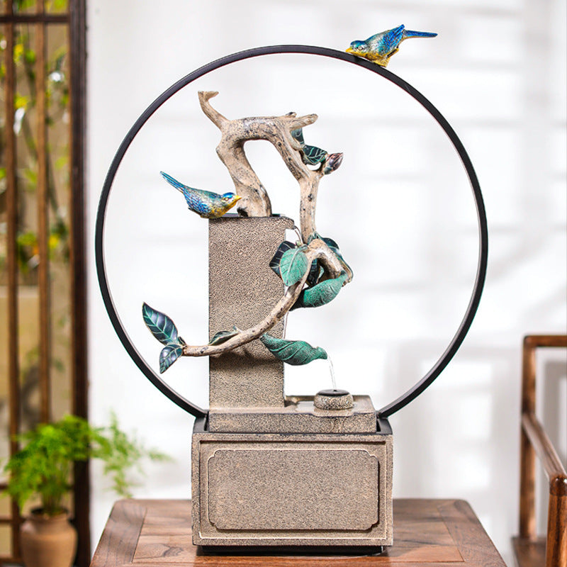 Decorative fountain with birds and branches on a wooden surface