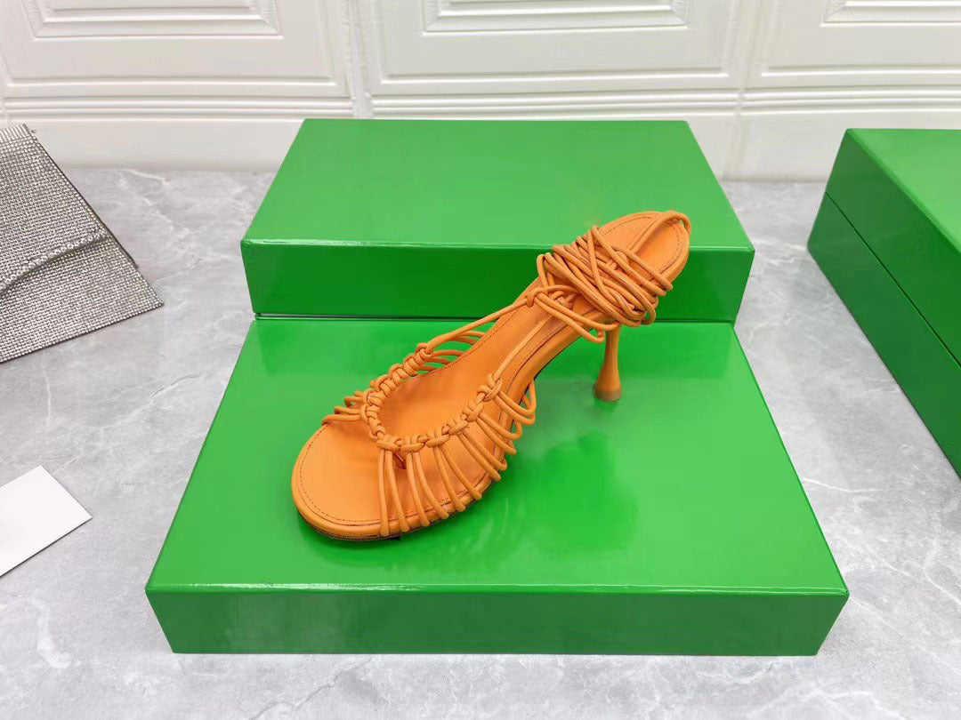 Orange sandal on a green platform with a white textured background