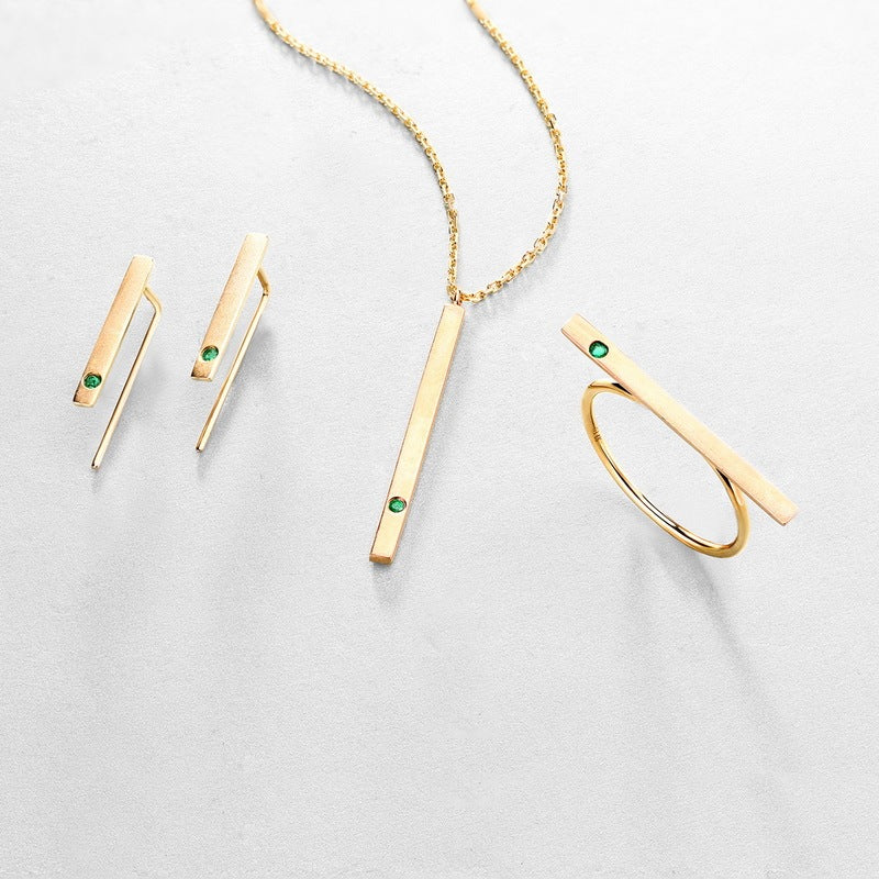 Gold jewelry set with necklace, earrings, and ring on a light gray background