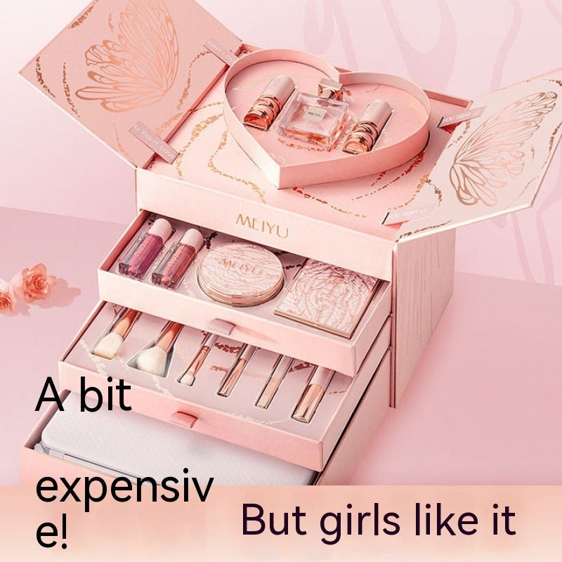 Pink makeup set with various items including lipsticks, a perfume bottle, and brushes, on a pink background.