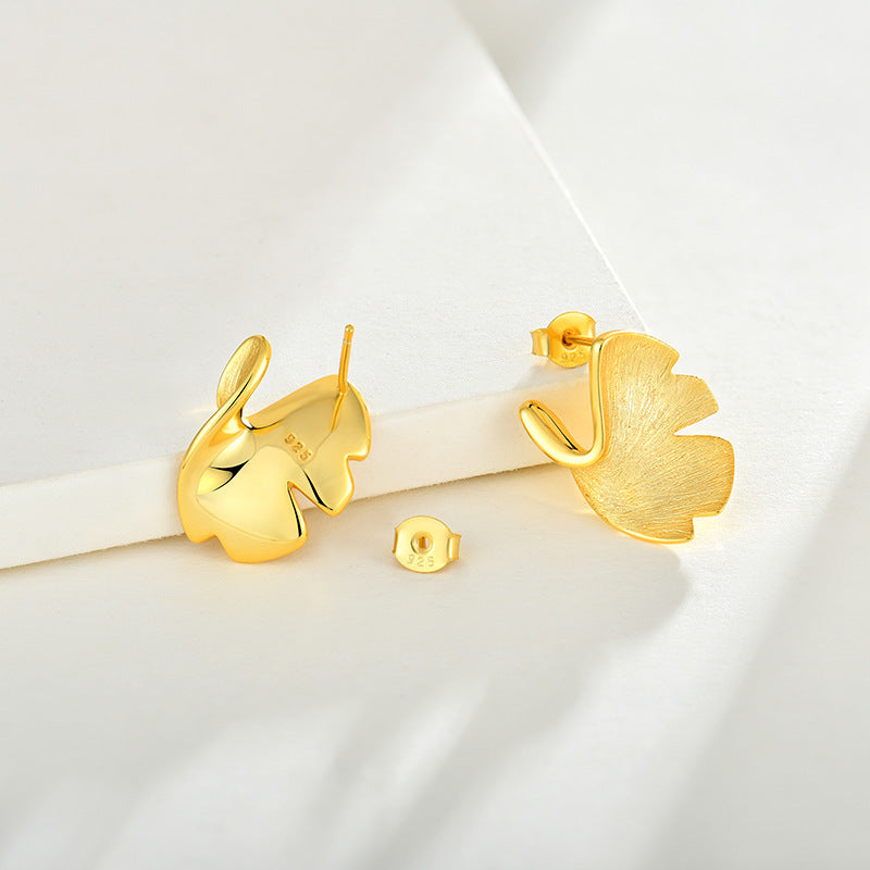 Gold leaf-shaped earrings on a white background