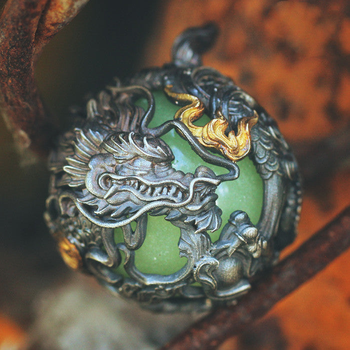 Decorative pendant with dragon design on a green sphere, close-up shot.