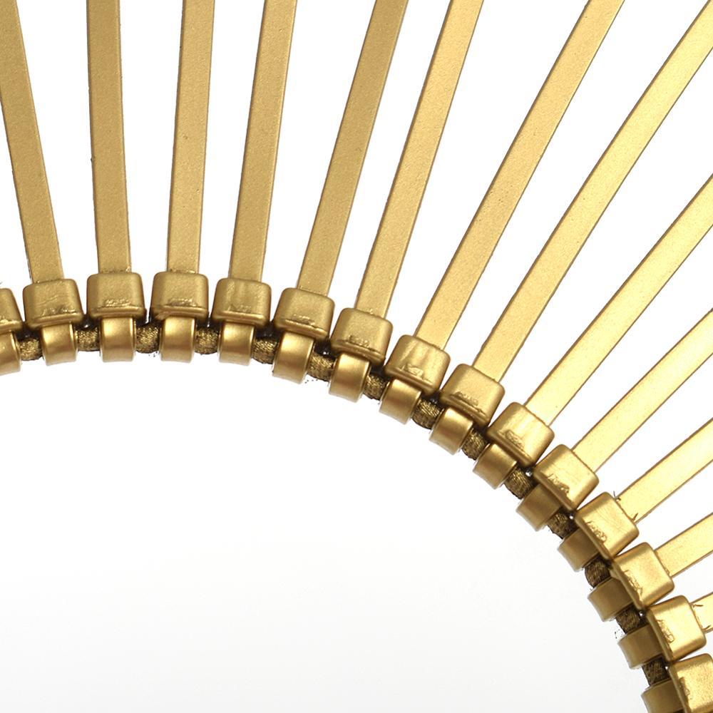 Close-up of a gold decorative ring with cylindrical elements on a white background