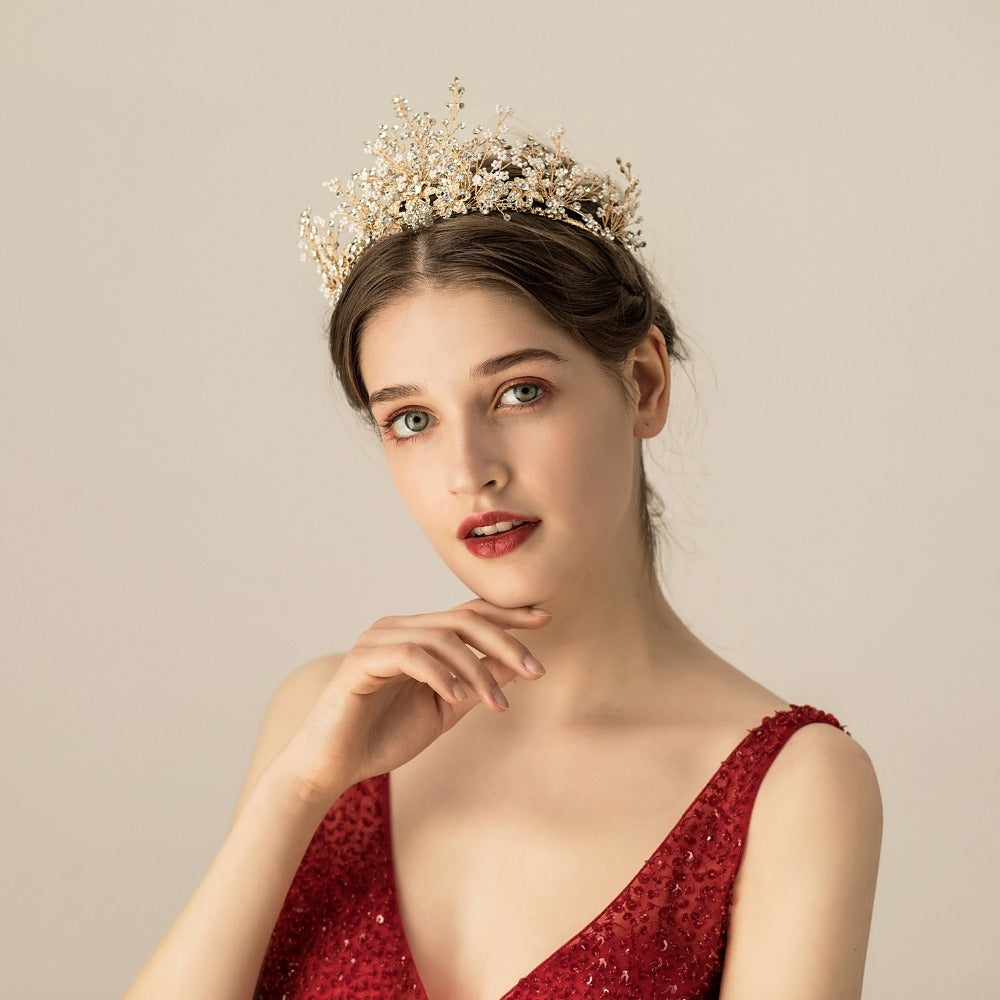 Woman wearing a gold tiara and red dress against a beige background