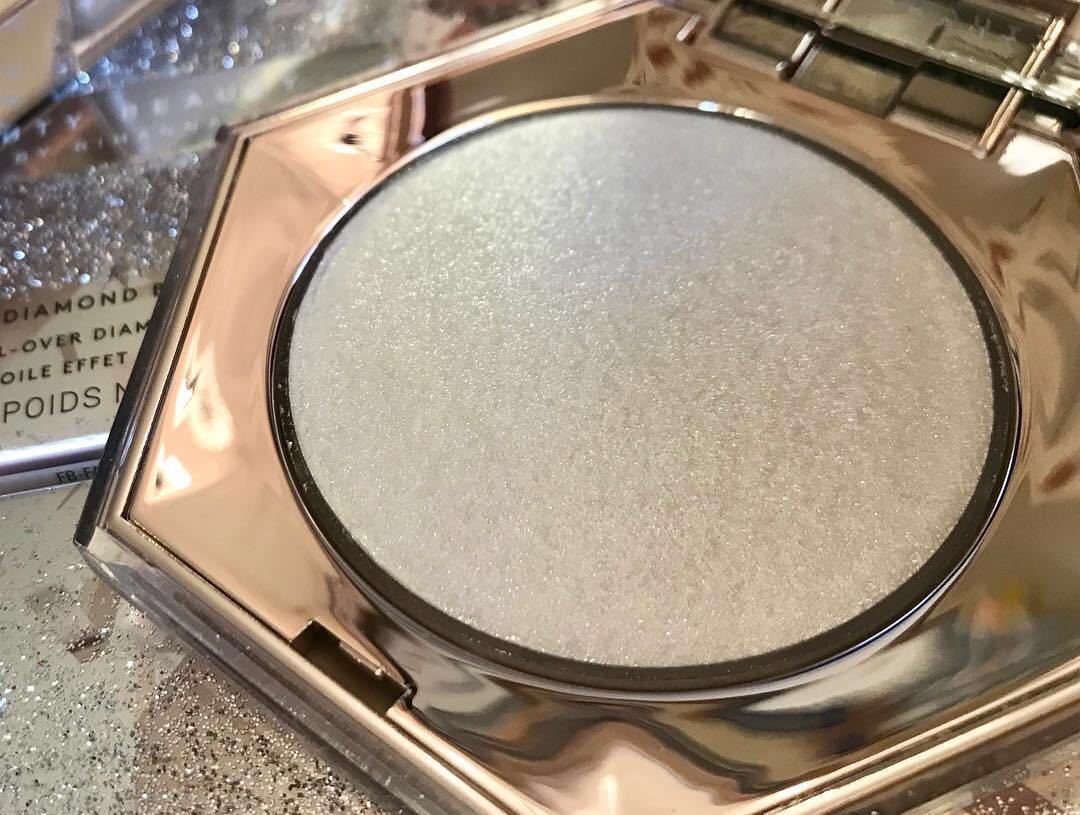 Compact powder in a rose gold case with a mirror on a reflective surface.
