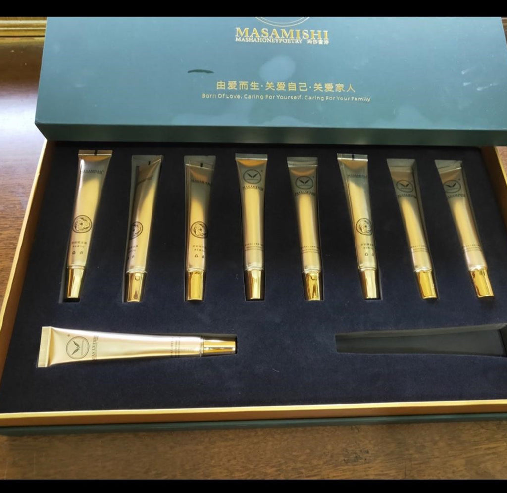 Set of gold cosmetic tubes in a Masamishi branded box on a wooden surface
