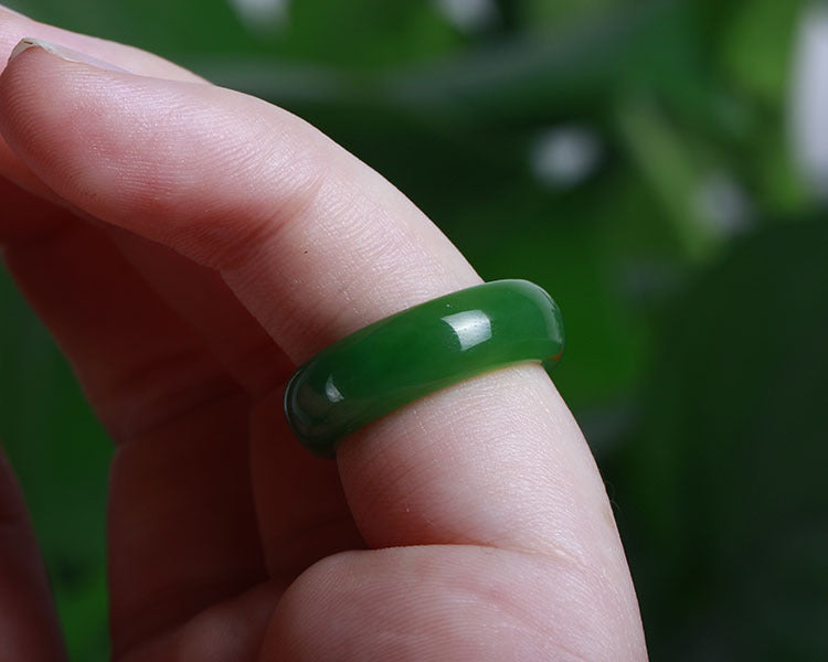 Green jade ring on a finger with a blurred green background