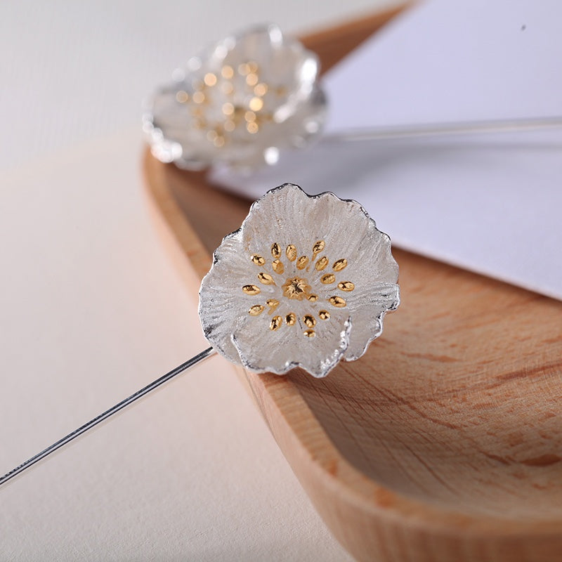 Silver and gold floral hairpin on a wooden surface