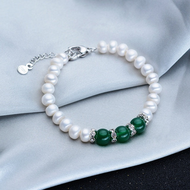 Pearl bracelet with green beads on a light gray fabric background