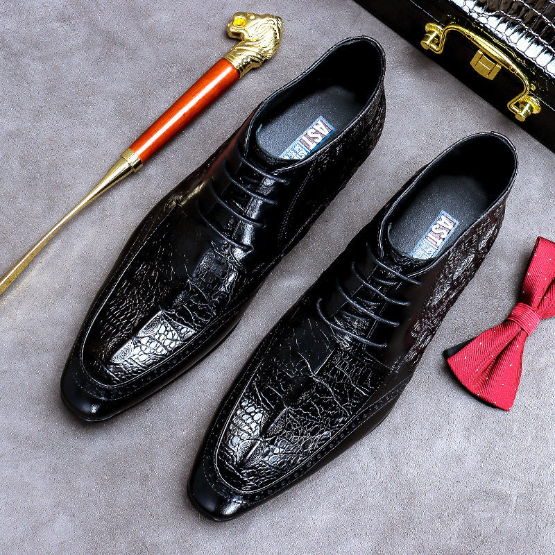 Black leather dress shoes with a textured toe, accompanied by a red bow tie and gold-handled shoe brush on a gray surface.