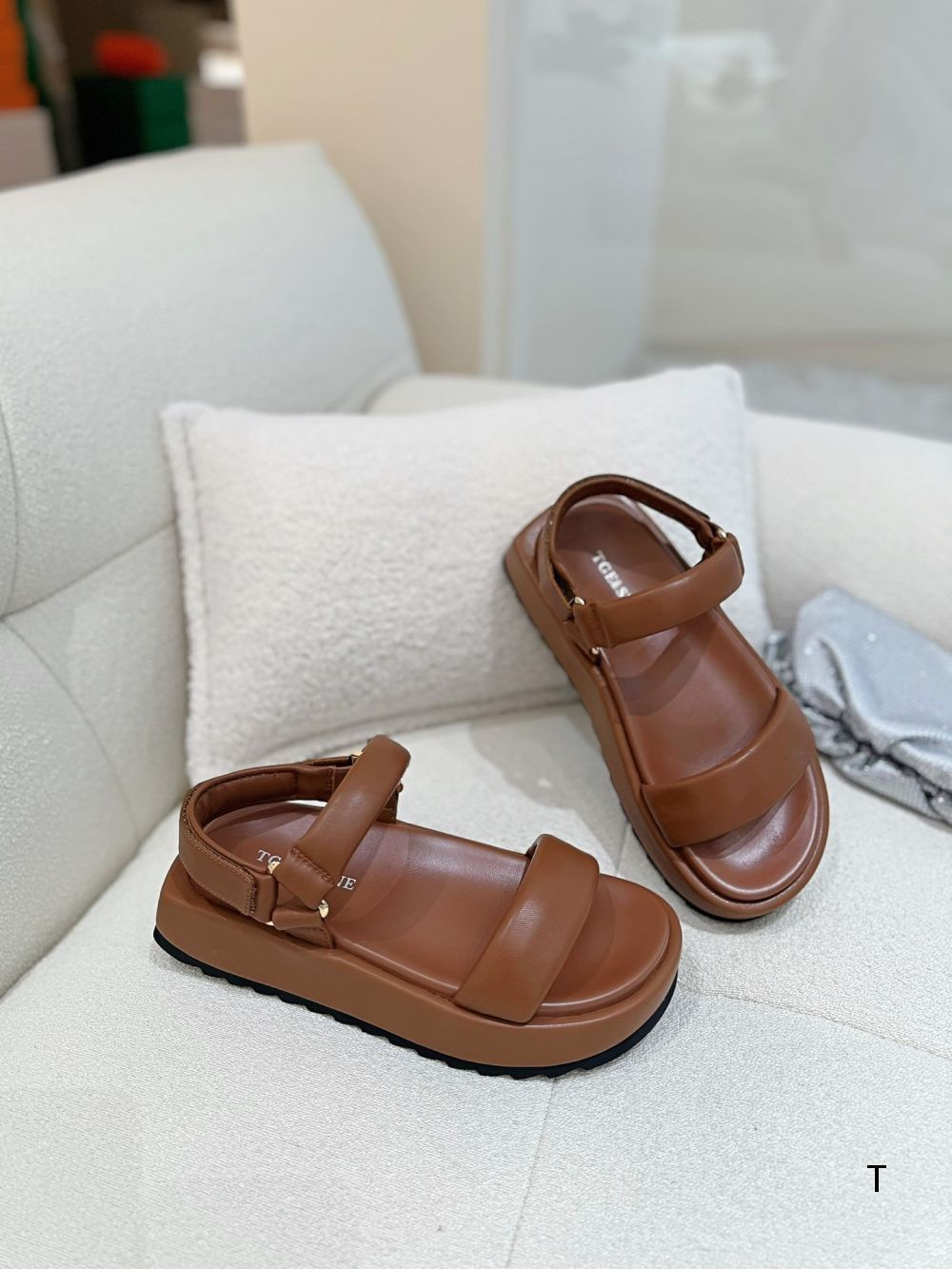 Pair of brown sandals on a white surface with a blurred background