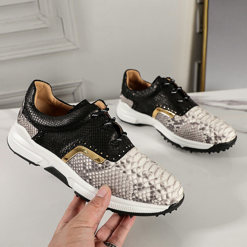 Black and white sneakers with gold accents held by a hand against a neutral background