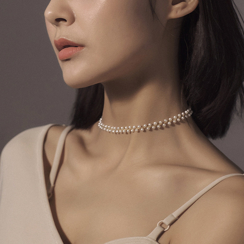 Close-up of a woman wearing a pearl necklace against a neutral background