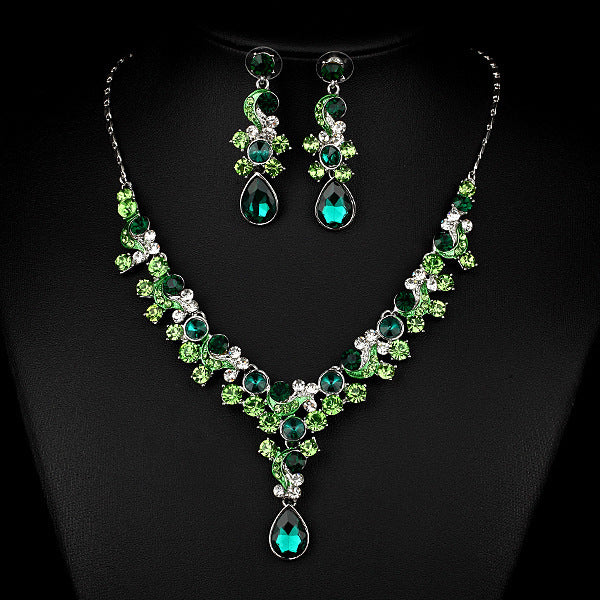 Green gemstone necklace and earrings on a black background