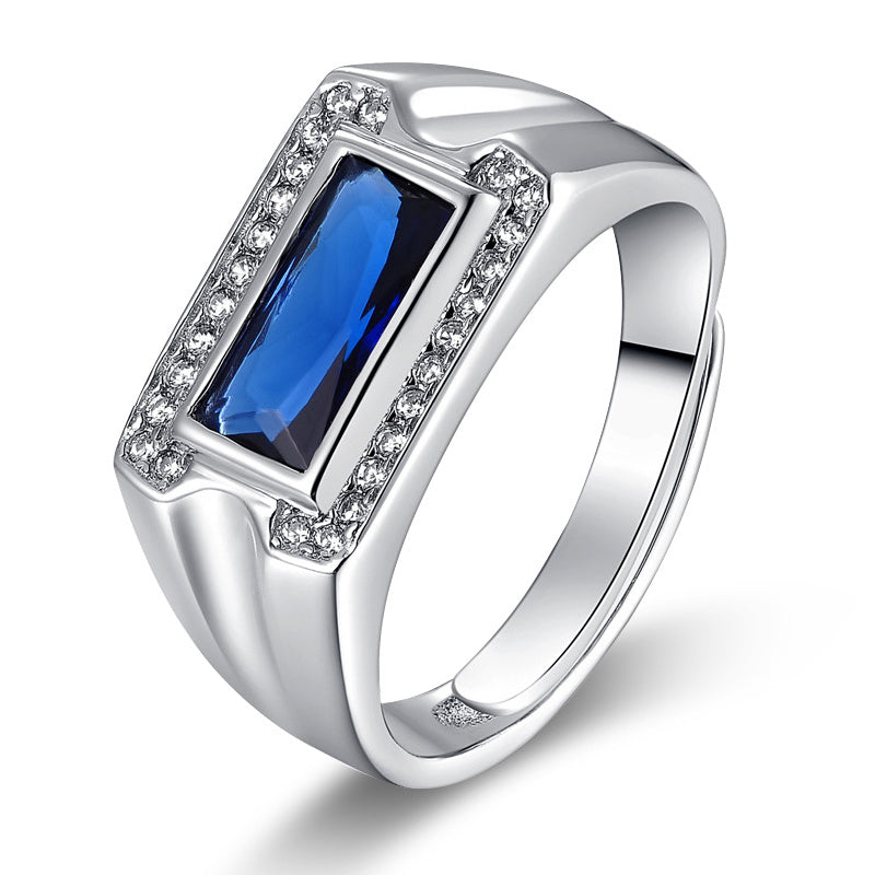 Silver ring with a blue gemstone and clear stones on a white background