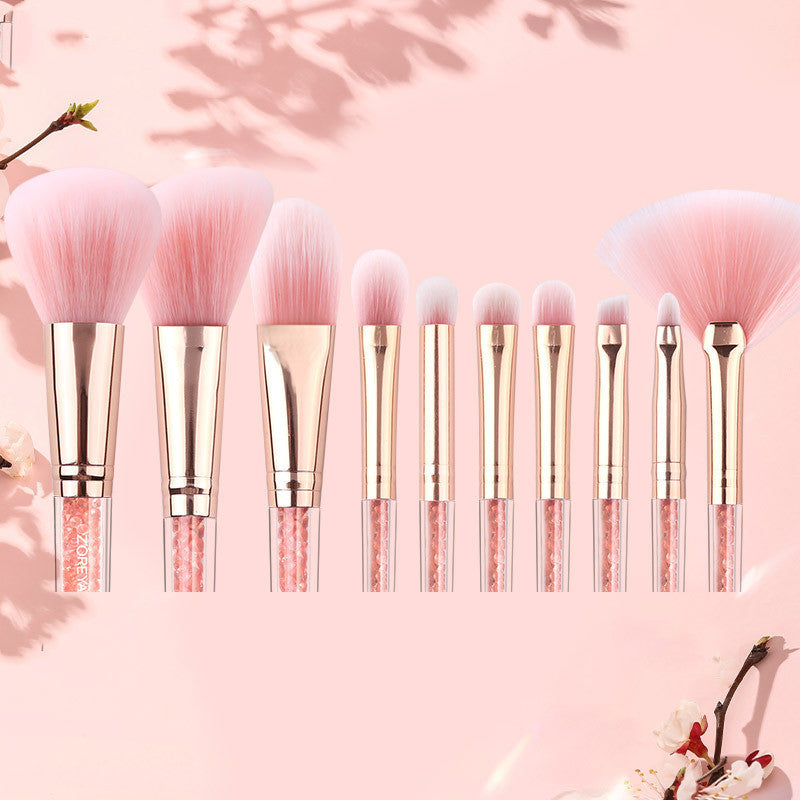 Set of makeup brushes with pink bristles and glittery handles on a pink background