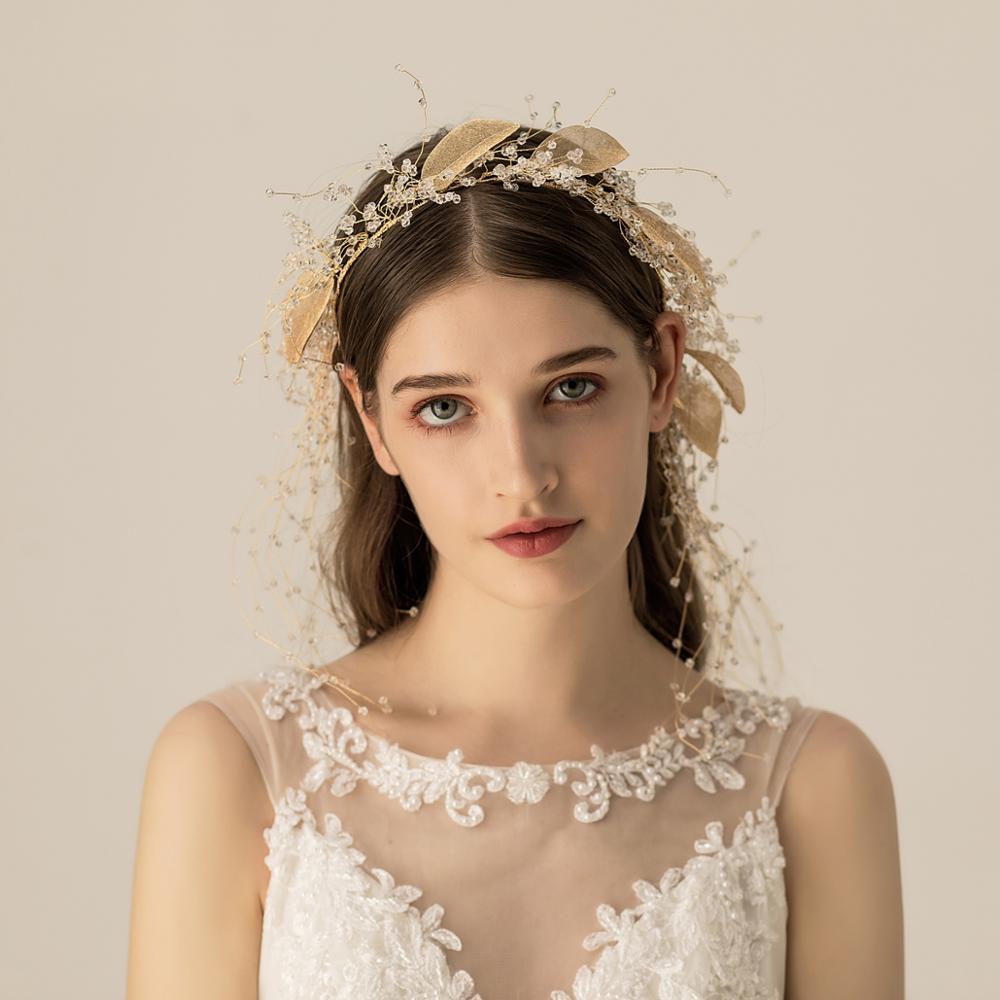 Woman wearing a delicate headpiece and lace dress against a neutral background