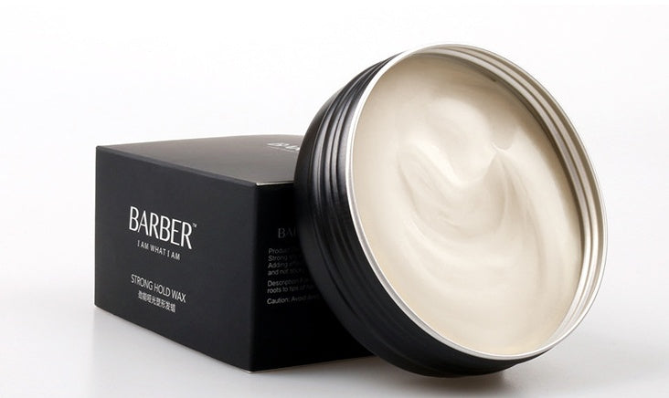 Black container of hair wax with a white lid on a white background