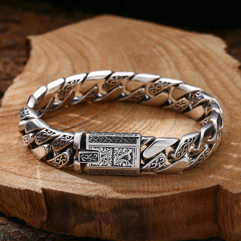 Silver bracelet with intricate designs on a wooden surface