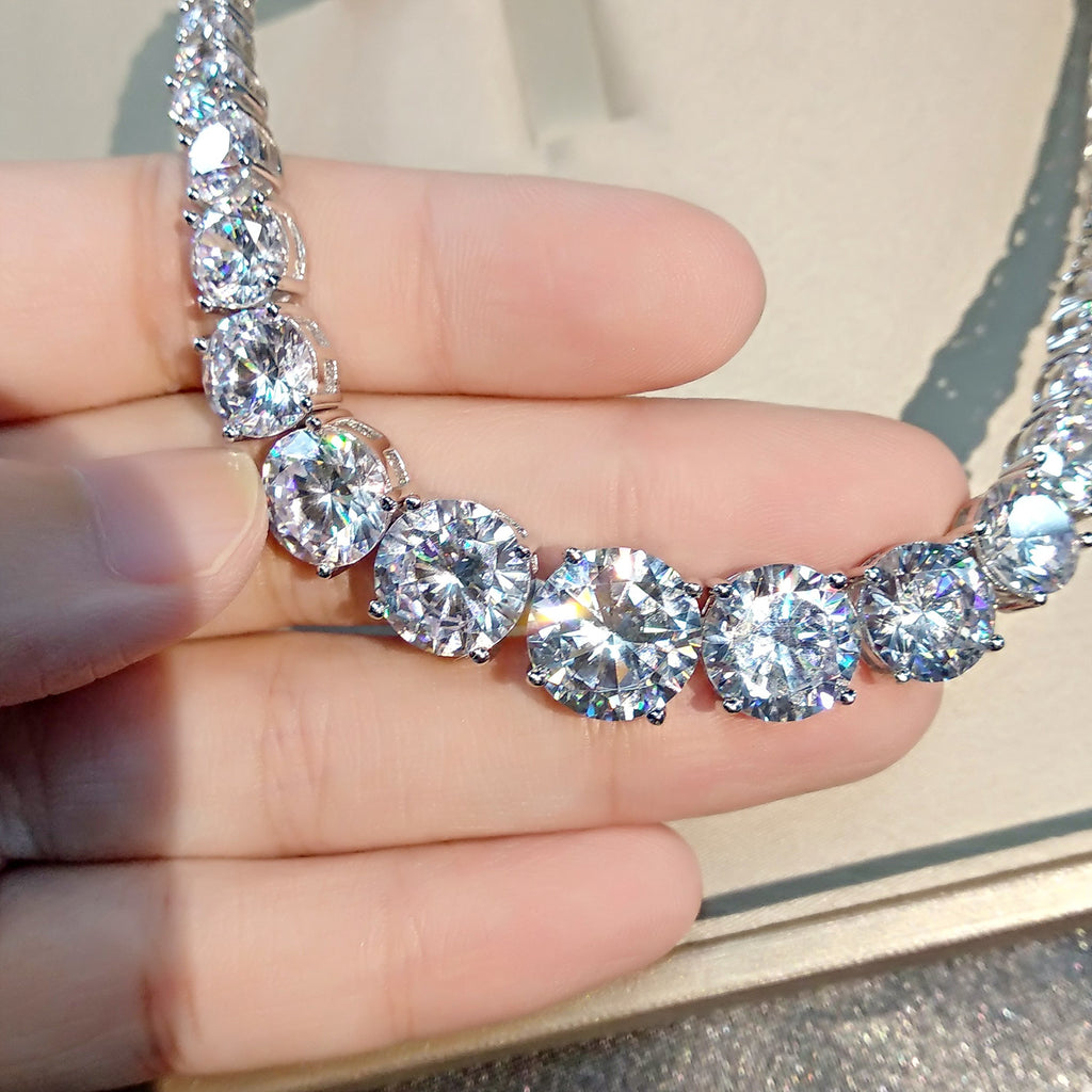Diamond necklace held by a hand against a neutral background