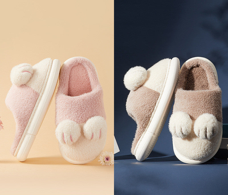 Pair of pink fuzzy slippers with paw-like toes on a beige background, and a pair of brown fuzzy slippers with paw-like toes on a blue background.