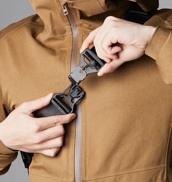 Person adjusting a black zipper on a brown jacket against a gray background